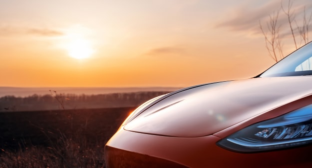 capot de voiture avec un coucher de soleil en fond