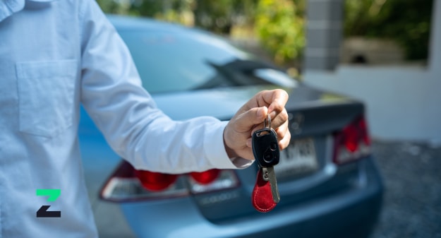 personne qui tient des clés de voiture en main devant une voiture
