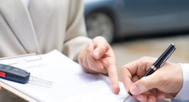 mains qui signent un contrat avec une clé de voiture dessus