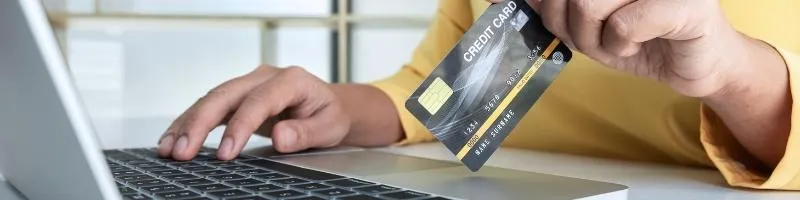 personne avec une carte bancaire face à un ordinateur